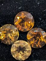 Four round yellow-orange gemstones on black background