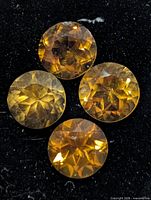 Four round faceted citrine gemstones on black background