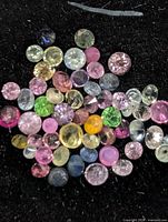Loose multicolor tourmaline stones spread on black background