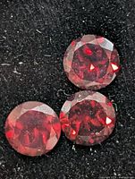 Three round red garnet gemstones on black foam