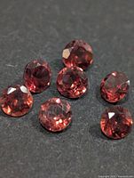 Seven round faceted garnets on dark surface