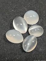 Five oval cabochon moonstones on dark background