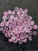 Pile of round pink sapphires on black background