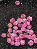 Close-up of loose round faceted rubies on black background