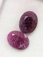 Two oval faceted rubies on white background