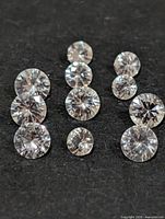 Eleven round faceted white sapphires arranged on dark background