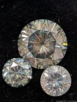 three loose round moissanite gemstones close-up on black background