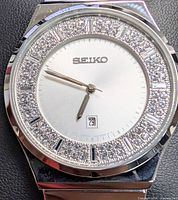 Close view of dial showing crystal bezel, silver dial, date window