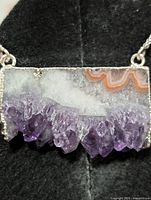 Close view of pendant front showing amethyst druzy crystals, agate banding, silver setting