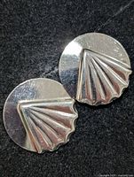 front view of the two round silver earrings displaying fan motif