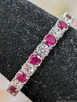 Close-up of alternating red and clear CZ stones on silver band