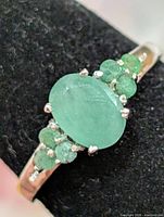 Front view of silver ring showing oval emerald and accent stones