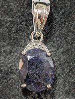 Front view of silver pendant highlighting dyed sapphire and accent stones