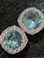 Front view showing both earrings with blue CZ centers and clear CZ halos