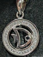 Front view of round silver pendant with CZ border and fish cut-out