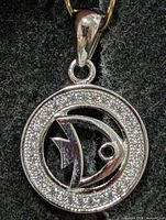 front view of round silver pendant with CZ border and fish design