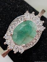 top view of emerald and CZ halo ring on display stand