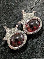 Front view of both earrings showing garnet stones and crown accents