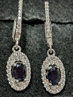 Front view showing sapphire centers and CZ halos on both earrings