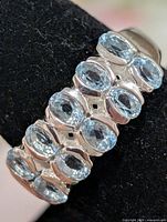 oblique view of ring showing cluster of blue topaz stones on band