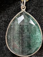 Front view of pear-shape emerald pendant in silver bezel