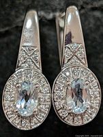 Front view showing blue topaz centers, CZ halo, and pavé shoulders