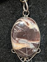 Front view of oval coconut jasper pendant in silver setting