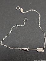 Full view of silver bracelet laid flat showing arrow motif and clasp