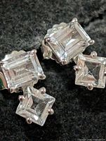 Front view showing emerald-cut top stones and princess-cut drops