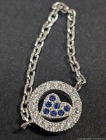 front view of silver CZ pendant with clear stones and blue heart, chain attached