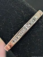 Front view of silver band ring displaying channel-set cubic zirconia stones