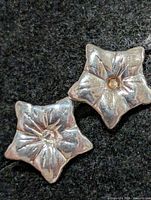 Front view of both silver star earrings showing raised design and center stones