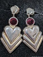 Front view of both silver heart earrings with pink stones on black background