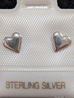 Front view of heart-shaped sterling silver stud earrings on display card