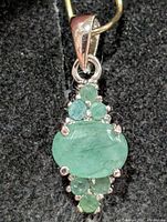 Front view of sterling silver pendant with emerald stones
