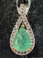 Front view of teardrop pendant showing emerald centre and topaz halo