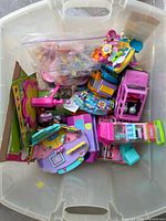 Plastic tote containing multiple Polly Pocket playsets, vehicles and accessories