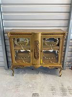 Full front view of cabinet showing glass panels, carved details and legs