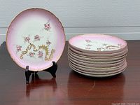 Stack of pink floral Limoges plates with one displayed on stand