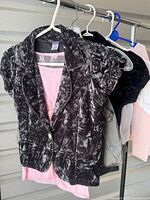 Front view of black crushed-velvet blazer layered over pink lace top on hanger