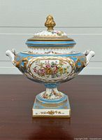 Front view of porcelain urn with lid, handles and painted bird motif