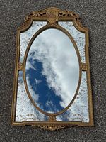 Full view of gilt wood oval wall mirror on ground