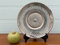 Front view of sterling silver pierced bowl on stand with apple for scale