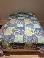 Queen bed covered with multicolour patchwork quilt and matching pillowcases