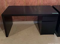 Front view of black desk showing full width and storage pedestal