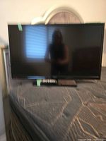 Front view of Insignia LED TV with remote on stand