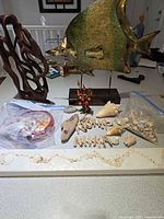 Overall view showing metal fish sculpture, wood sculpture, shells, driftwood and plaque