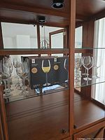 Two boxed sets of wine glasses and loose glasses inside cabinet