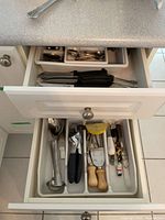 Open drawer showing mixed kitchen utensils including ladles, peelers, can opener, cheese tools and drawer organizer