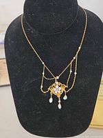 Full view of 10k gold necklace on display bust showing pendant, chain and pearl drops